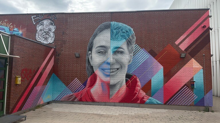 Graffiti Kunst des Ulmer Künstlers Milo. Ein Gesicht zur Hälfte Junge zur andern Mädchen auf der Fassade einer Ulmer Schule. 
