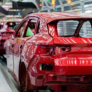 Mitarbeiter überprüfen im Lichttunnel der Lackiererei im Werk von Volkswagen den Lack einer Karosserie.