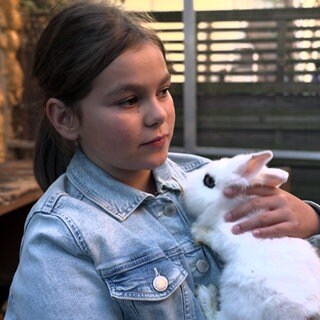 Mädchen hält weißes Kaninchen auf dem Arm. Auf dem Hof von Andrea Rotzoll helfen die Enkelkinder mit.