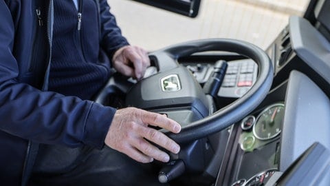 Ein Busfahrer sitzt am Lenkrad seines Fahrzeuges.