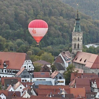 Ein Heißluftballon fliegt in Bad Urach knapp am Kirchturm vorbei