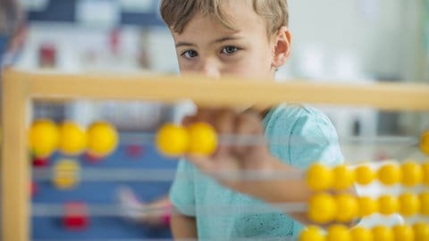 Unterschied zwischen Mädchen und Jungs in der Schule: Kind rechnet an Rechentafel in Mathe
