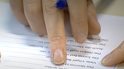 Finger zeigen auf Wörter. Lesen Lernen im Erwachsenenalter ist nicht leicht. 