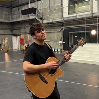 Sänger Myle singt und spielt auf seiner Gitarre.