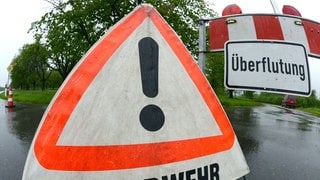 Ein Warnschild mit der Aufschrift "Überflutung" und ein Warndreieck der Feuerwehr. In Pfullendorf war die Feuerwehr nach Starkregen im Dauereinsatz.