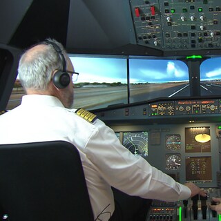 Nino Di Maiuta und Helmut Müller sitzen im Cockpit einer Flugsimulation.