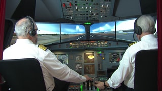 Nino Di Maiuta und Helmut Müller sitzen im Cockpit einer Flugsimulation.
