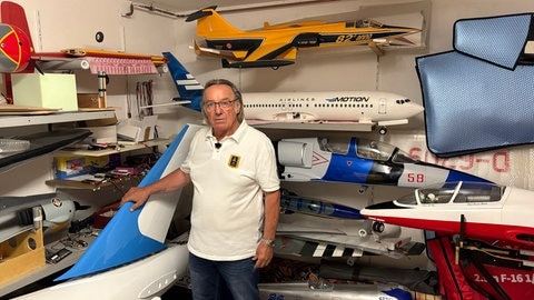 Organisator Adi Pitz vor mehreren selbst gebauten Modellen von Verkehrs- und Militärflugzeugen.