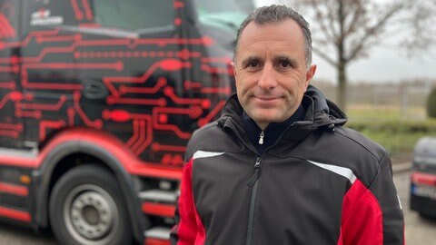 Geschäftsführer Rainer Schmitt von einer Spedition aus Bietigheim vor einem Elektro-LKW.