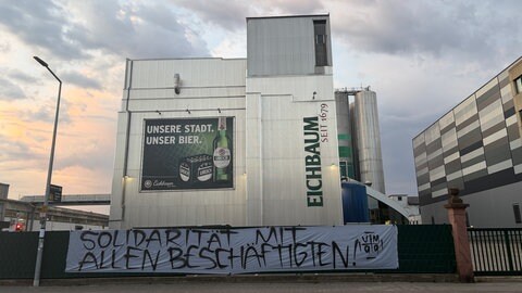 Ein Banner mit den Worten "Solidarität mit allen Beschäftigten" hängt vor dem Eichbaum-Gelände.