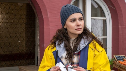 Jenny (Julia Obst) steht hinter dem Hofladen, sie hält einen kleinen Löffel in den Händen