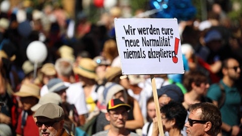 Protestplakat mit der Auffschrift: "Wir werden eure "neue Normalität" niemals akzeptieren!" - Tausende Menschen gehen aus Protest gegen die Corona-Einschränkungen im August 2020 in Berlin auf die Straße. Zur Demo aufgerufen haben die Stuttgarter Initiative Querdenken 711 und die Berliner Kommunikationsstelle Demokratischer Widerstand, eine Mischung aus Verschwörungstheoretikern, Rechtsextremen und Virusleugnern. Trotz geltender Hygienevorschriften tragen die Demonstranten nur sehr vereinzelt einen Mund-Nasen-Schutz und halten keinen Abstand zueinander.