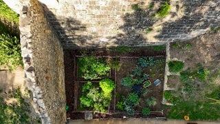 Aus der Vogelperspektive: Ein Mann arbeitet in einer Parzelle eines Burggartens. 