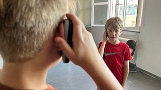 Zwei Jungen aus einer zweiten Klasse der Grundschule Schenkendorf üben, einen Notruf abzusetzen.