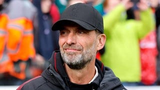 Jürgen Klopp steht mit Trainingsjacke und Kappe an der Trainerbank. 