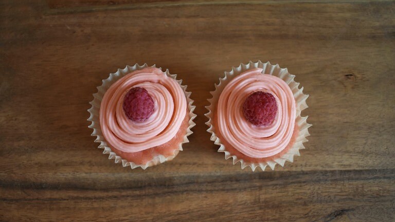 Zwei rosa Cupcakes mit Zuckerguss und Garnituren
