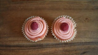Zwei rosa Cupcakes mit Zuckerguss und Garnituren