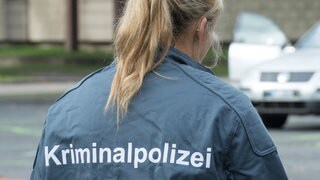 Rücken einer Frau. Sie trägt eine Jacke mit der Aufschrift: Kriminalpolizei. Bis heute gibt es bei der Kripo deutlich weniger Kolleginnen als Kollegen. Auch, weil ermittelnde Polizistinnen lange mit dem Vorurteil zu kämpfen hatten, Frau-Sein und Staatsgewalt passten nicht zusammen.