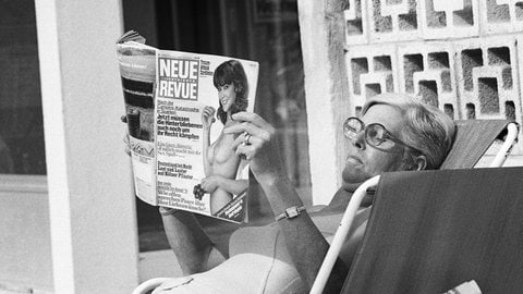 Siebziger Jahre, Schwarzweissfoto, Frau liegt in einem Liegestuhl und liest eine Illustrierte
