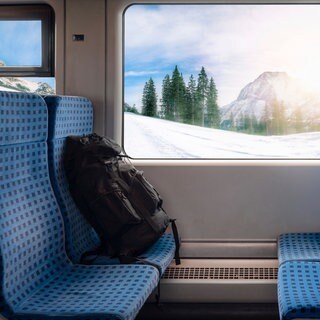 Bahnsitze mit Rucksack und Winterlandschaft im Hintergrund