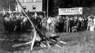 Deutsche und französische Studenten verbrennen am 8.8.1950 im Niemandsland zwischen St. Germanshof (deutsche Seite) und Wissembourg (französische Seite) auf einem Scheiterhaufen Grenzpfähle und Schilder, die sie zuvor an dem grenzübergang demontiert hatten. In einer Proklamation forderten sie die Bildung eines europäischen Parlaments und einer europäischen Regierung.