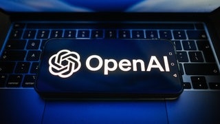 Auf dieser Fotoillustration ist das OpenAI-Logo auf einem Smartphone zu sehen, das auf einem Laptop liegt. 