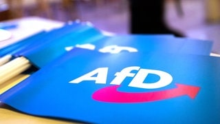 Fähnchen mit dem Logo der AfD liegen auf einem Tisch.
