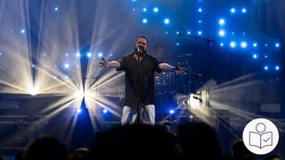 Marian Gold von der Band Alphaville. Er steht auf einer Bühne. Rechts das SWR Logo für Leichte Sprache.