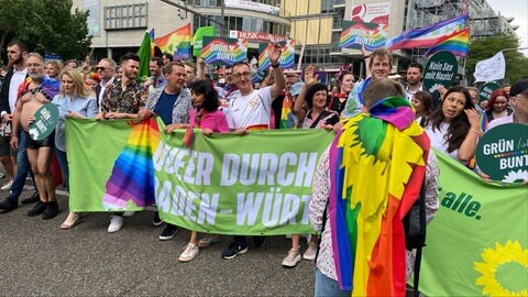 Landtagspräsidentin Muhterem Aras (Grüne) und der Grünen-Spitzenkandidat für die kommende Landtagswahl, Cem Özdemir, laufen nebeneinander in einer Gruppe beim CSD Stuttgart 2025 mit. 