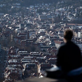 Zwei junge Frauen sitzen am Rande einer Aussichtsplattform mit Blick über Stuttgart in der Sonne: In Stuttgart führt die Reform der Grundsteuer zu Ärger. Ein Grund dafür sind die sogenannten Bodenrichtwert-Zonen.