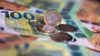 Geldscheine und Münzen liegen auf einem Tisch. Ministerpräsident Schweitzer (SPD) hat eine "historische Investitionsoffensive" für die rheinland-pfälzischen Kommunen angekündigt.