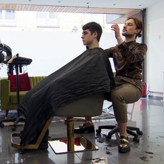 Friseur Dennis Boloban aus Karlsruhe ist Hair-Influencer. Er sitzt im Friseursalon und schneidet einem Kunden die Haare.