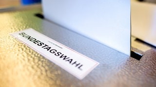 Ein Wahlzettel wird in eine Wahlurne für die Bundestagswahl geworfen. Am Bodensee werben Unternehmen für die Wahl demokratischer Parteien.