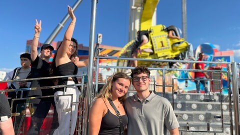 Lucy (18) und Philip (19) stehen vor dem Fahrgeschäft "Booster Maxxx" beim Stuttgarter Frühlingsfest.