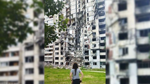 Daria Lunina steht vor einem zerstörten Haus bei ihrem Besuch in Charkiw 2023