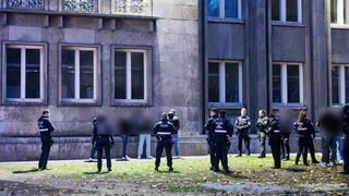 Mehrere Polizisten umzingeln am Stadthaus in Mainz eine Gruppe Männer, die einen Polizisten angegriffen haben soll.