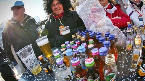 Auf einem Stehtisch stehen unzählige alkoholische Getränke, die Narren bedienen sich