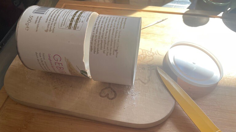 Den Deckel abnehmen und den Behälter seitlich auf den Tisch legen. Mit einem scharfen Messer etwa 7 cm unterhalb vom oberen Gefäßrand einen Ring schneiden.