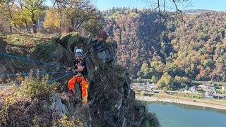 Kletterer lösen Steine am Loreleyfelsen, um ihn zu sichern.