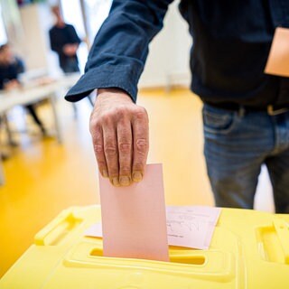 Mann wirft seinen Wahlzettel in die Wahlrurne