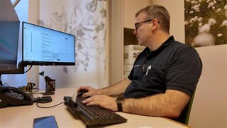 Hausarzt Wolfgang von Meißner sitzt am Schreibtisch. Durch den Einsatz von KI in seiner Praxis hat er wieder mehr Zeit für seine Patienten.