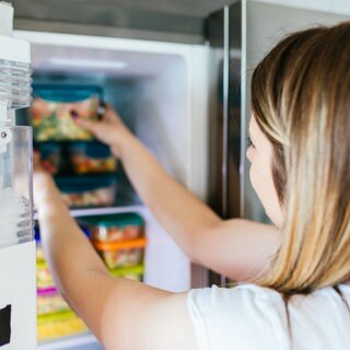 Richtig einfrieren: Eine Frau stellt eine Box ins Tiefkühlfach