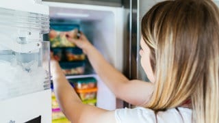 Richtig einfrieren: Eine Frau stellt eine Box ins Tiefkühlfach