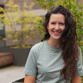 Frau mit grünem T-Shirt und dunklen Locken.