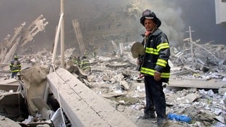 Ein Feuerwehrmann steht nach den Anschlägen des 11. September 2001 in New York mit einer Schaufel in den Trümmern eines Gebäudes