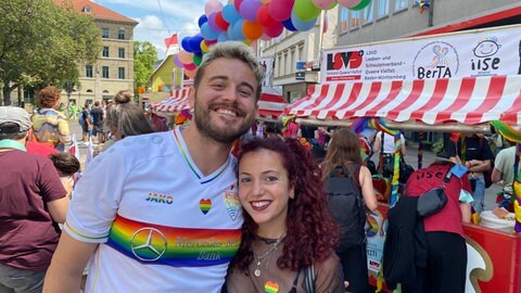 Lukas und Francesca lächeln beim CSD Stuttgart 2025 in die Kamera.