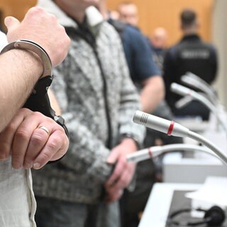 Hände in Handschellen: Die neun Angeklagten sogenannten Reichsbürger werden im Oberlandesgericht Stuttgart-Stammheim in den Gerichtssaal geführt.