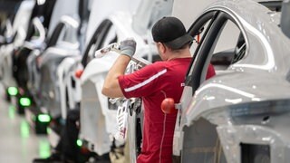 Ein Mitarbeiter montiert im Stammwerk in Zuffenhausen der Porsche AG einen vollelektrischen Porsche Taycan. Ab dem ersten April passt Porsche seine Regelungen zur Arbeitssicherheit im Werk Zuffenhausen an. Handys und In-Ear-Kopfhörer dürfen dann während der Arbeitstätigkeit nicht mehr genutzt werden.