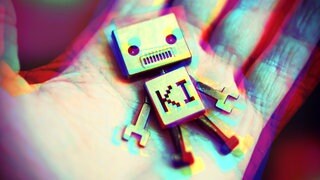 Roboter mit Aufschrift KI liegt auf einer menschlichen Hand. 