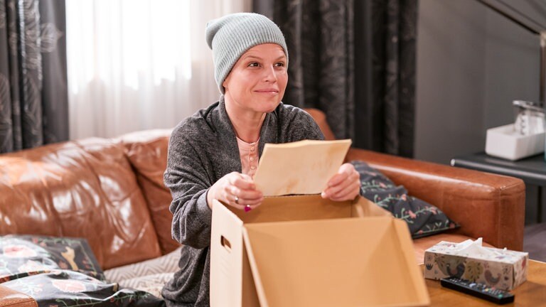 Die kranke Eva (Lucie Muhr) sitzt vor einem großen Karton